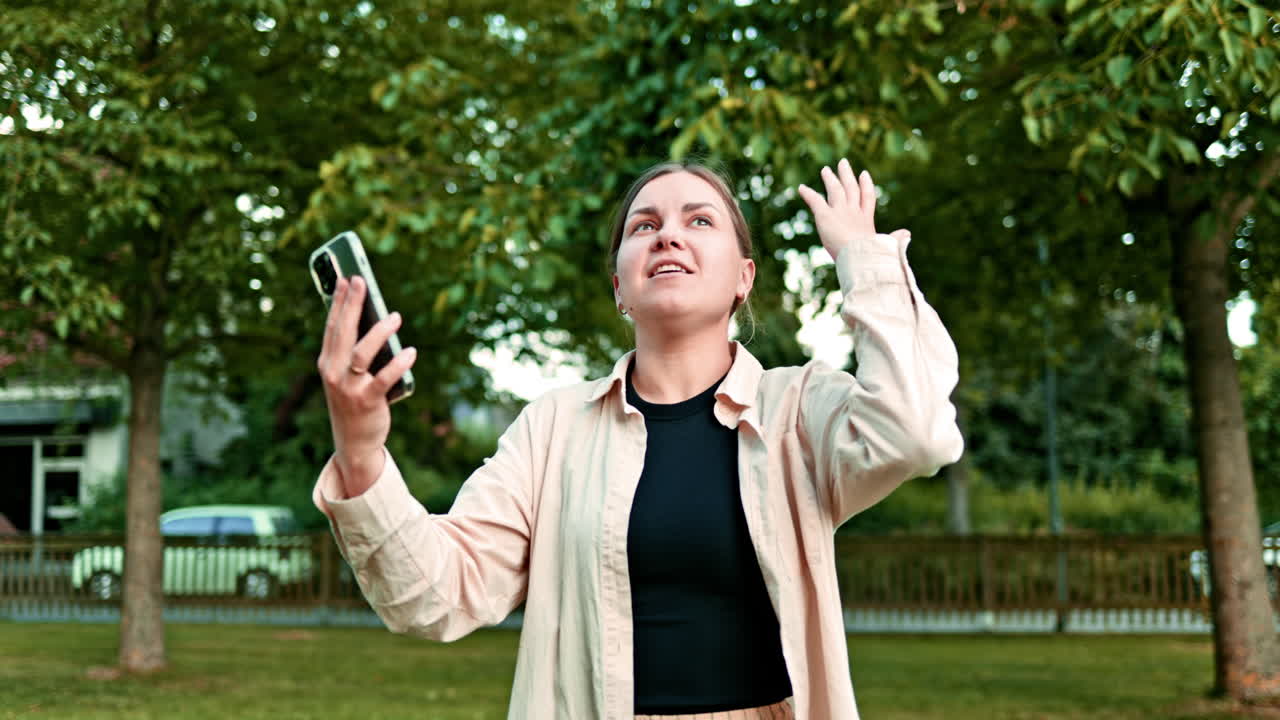Donna positiva che parla al telefono mentre si gode l'estate al parco. Donna casual che parla con lo smartphone sullo sfondo della natura, godendosi una giornata di sole.
