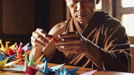 elderly monk creating origami cranes