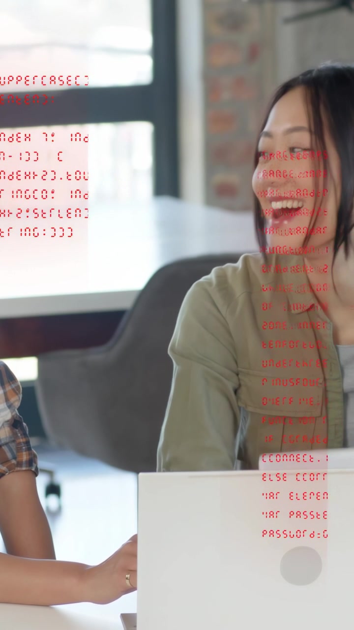 Vertical video: Woman on right turning after red code overlay on laptop, colleague reviewing code