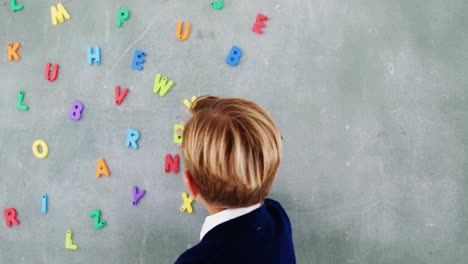 Boy-sticking-alphabet-b-on-chalkboard