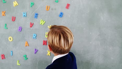 niño pegando el alfabeto b en la pizarra