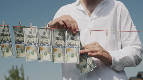 a man removes banknotes from a clothesline. money laundering concept