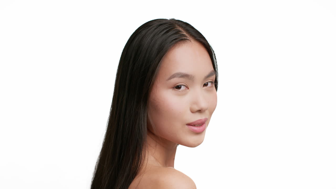 Portrait of a beautiful young Asian woman with long dark hair looking over her shoulder