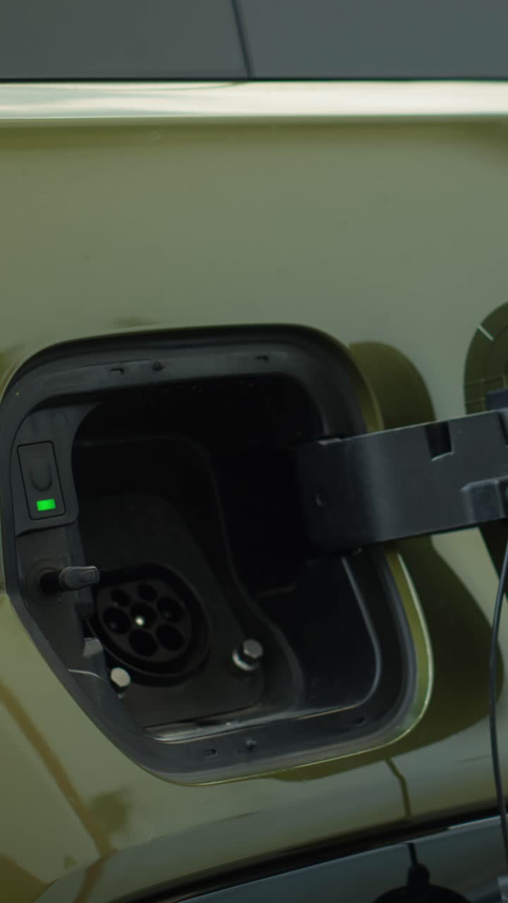 Vertical video Close up of driver connecting EV plug to electric car to recharge it