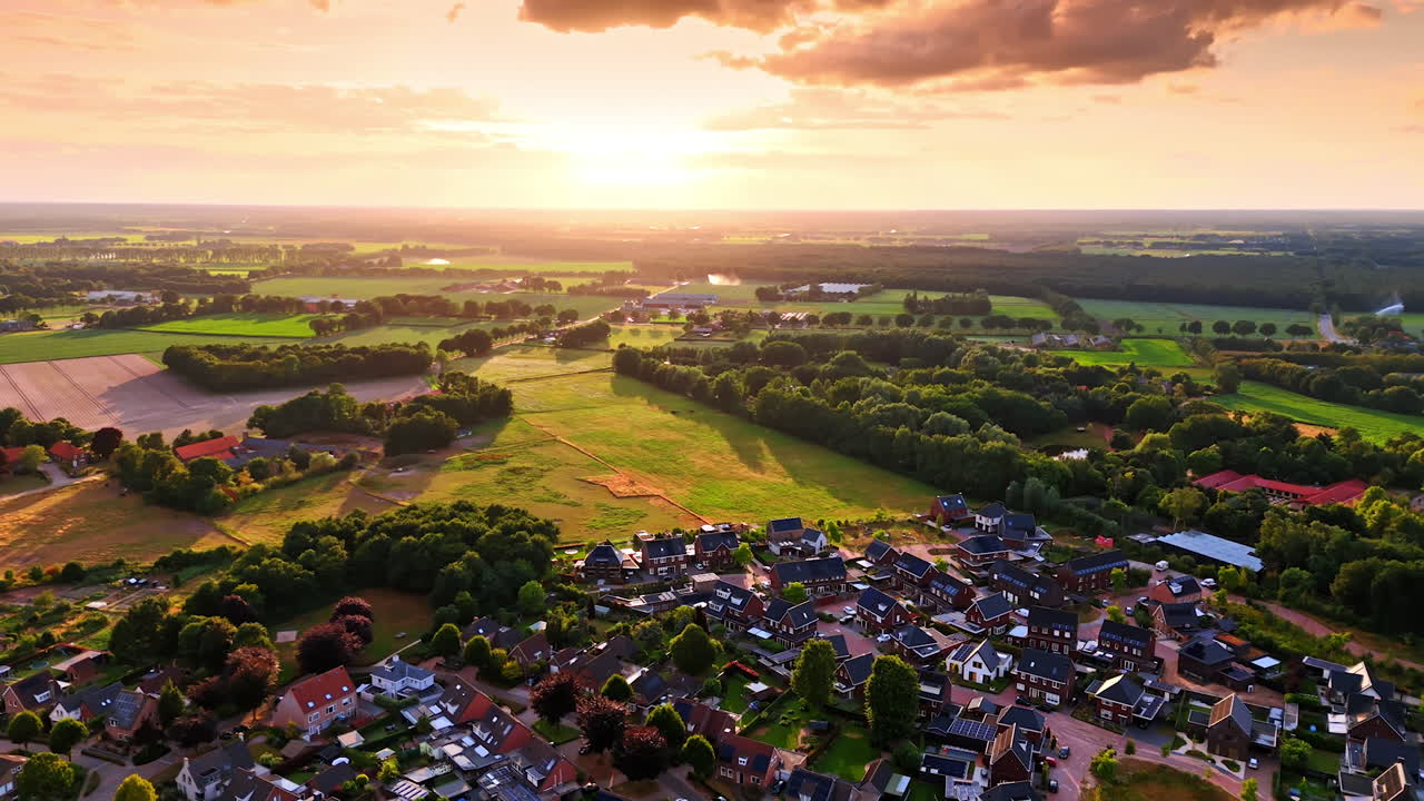 Sunset over rural village. A vibrant sunset casts warm colors over a peaceful village and lush fields, showcasing nature's beauty and tranquility