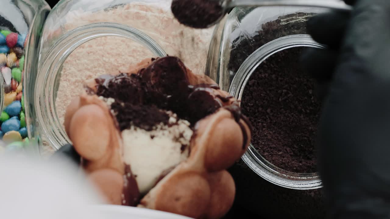 캔디 가게의 버블 와플에 초콜릿 스프링클을 붓는다