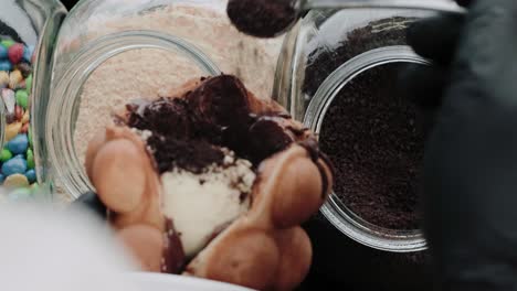 pouring chocolate sprinkles on a bubble waffle in a candy store
