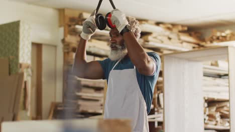 african american male carpenter removing protective ear-muffs in a carpentry shop