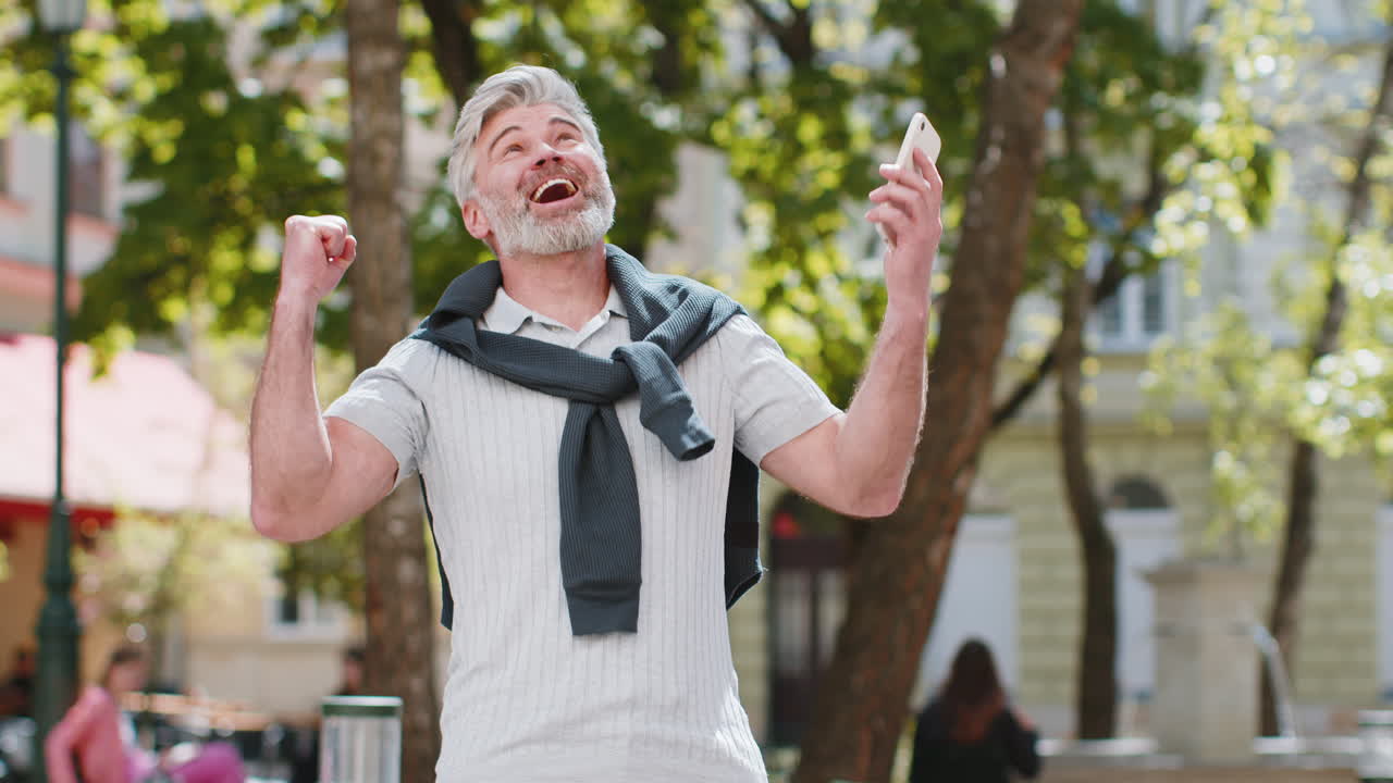 Old man use mobile smartphone celebrating win good message news lottery jackpot casino app victory