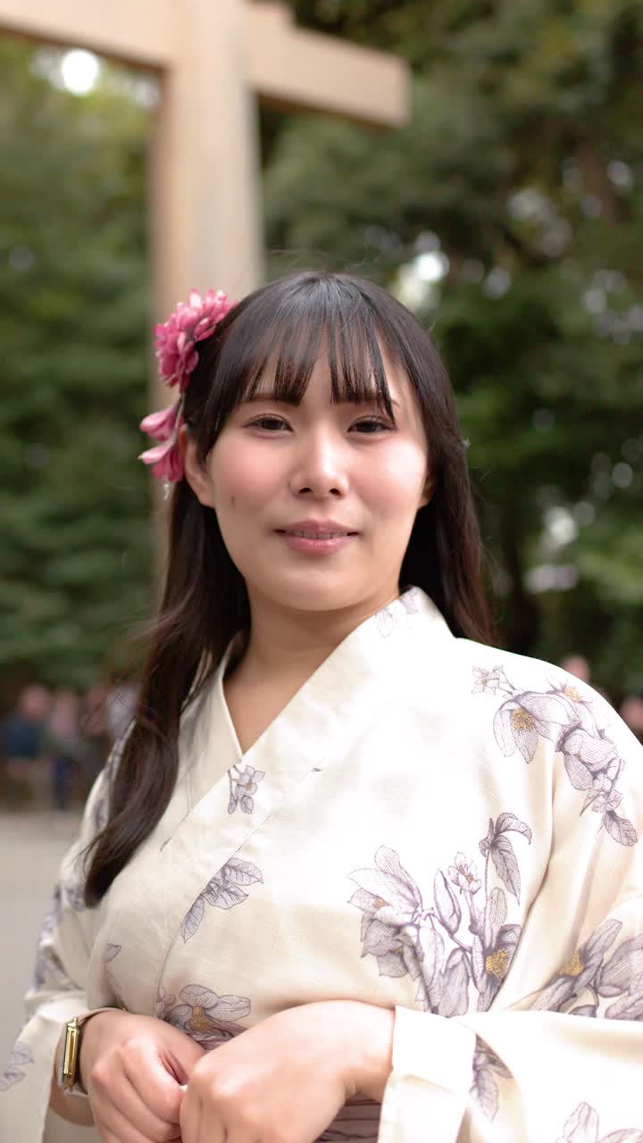 Una mujer con un yukata floral está de pie cerca de una puerta torii de un santuario sintoísta en Tokio, Japón