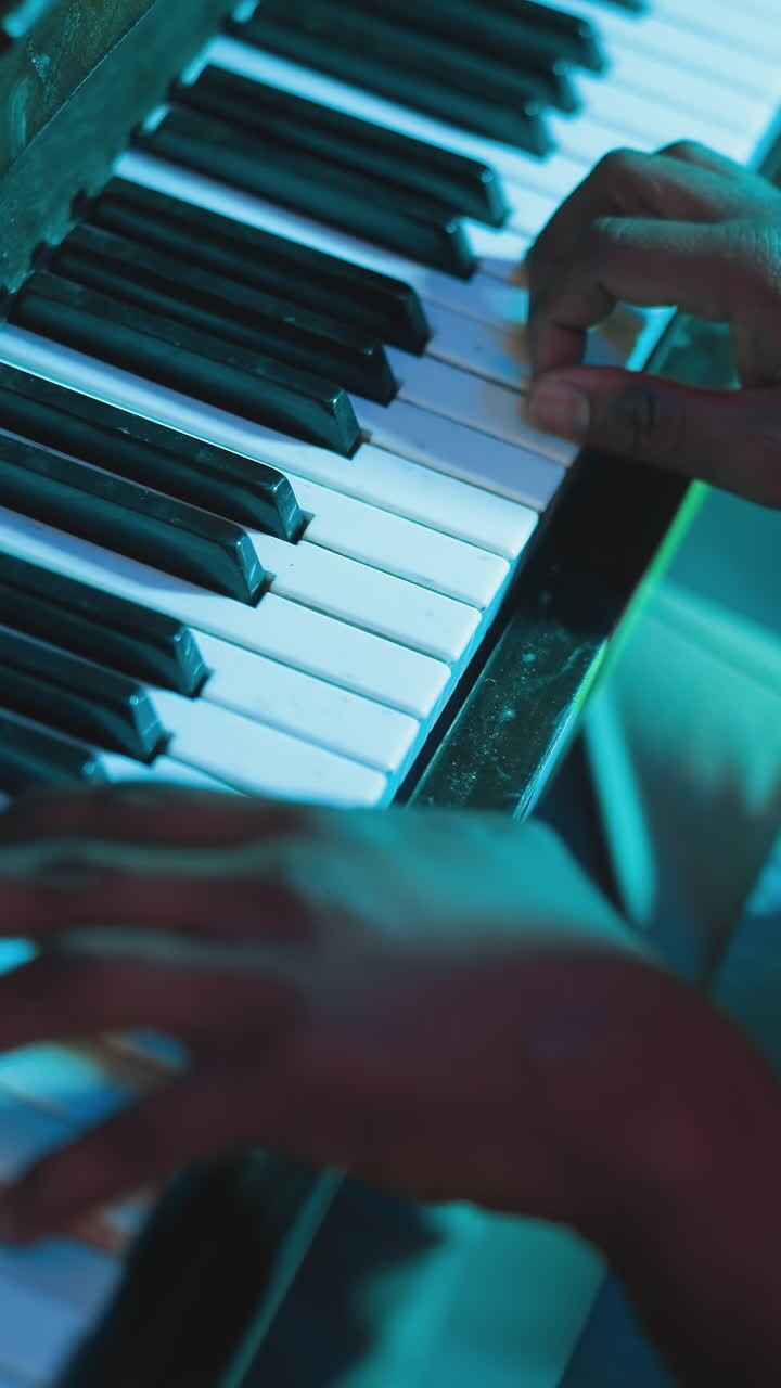 Lähikuva miehestä soittamassa musiikkikappaletta pianolla klubissa. Tarjoilija nauttii soittamisesta työvuoron jälkeen baarissa. Taiteellinen harrastus ja lahjakkuus.