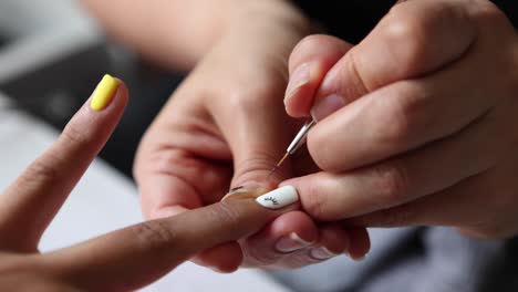 anonymous beautician applying lacquer on female client nails