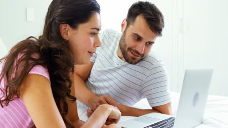 Couple-interacting-with-each-other-while-using-laptop-on-bed