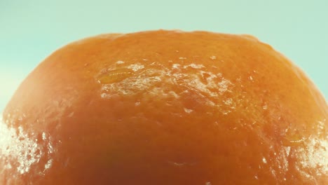 a macro shot of a clementine orange fruit on a rotating 360 stand, studio lighting, slow motion, 4k video