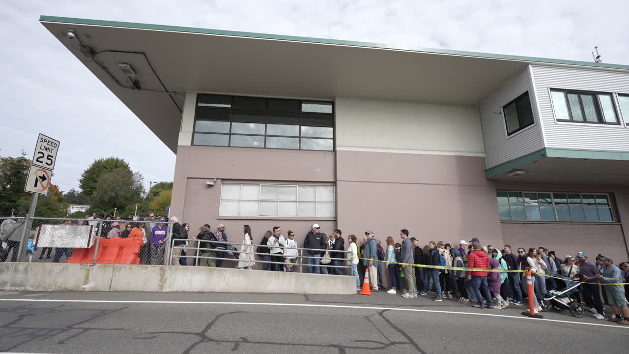 A crowd of people standing in line outside the Bainbridge Island ferry terminal, captured in a timelapse scene.