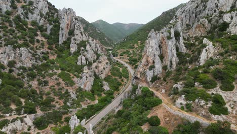 sharp pointed rocks reveal road to mainland of sardinia, italy - 4k aerial dolly forward