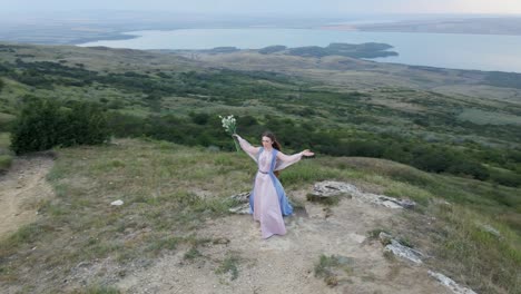 woman in a long dress stay along the mountain with a bouquet of flower