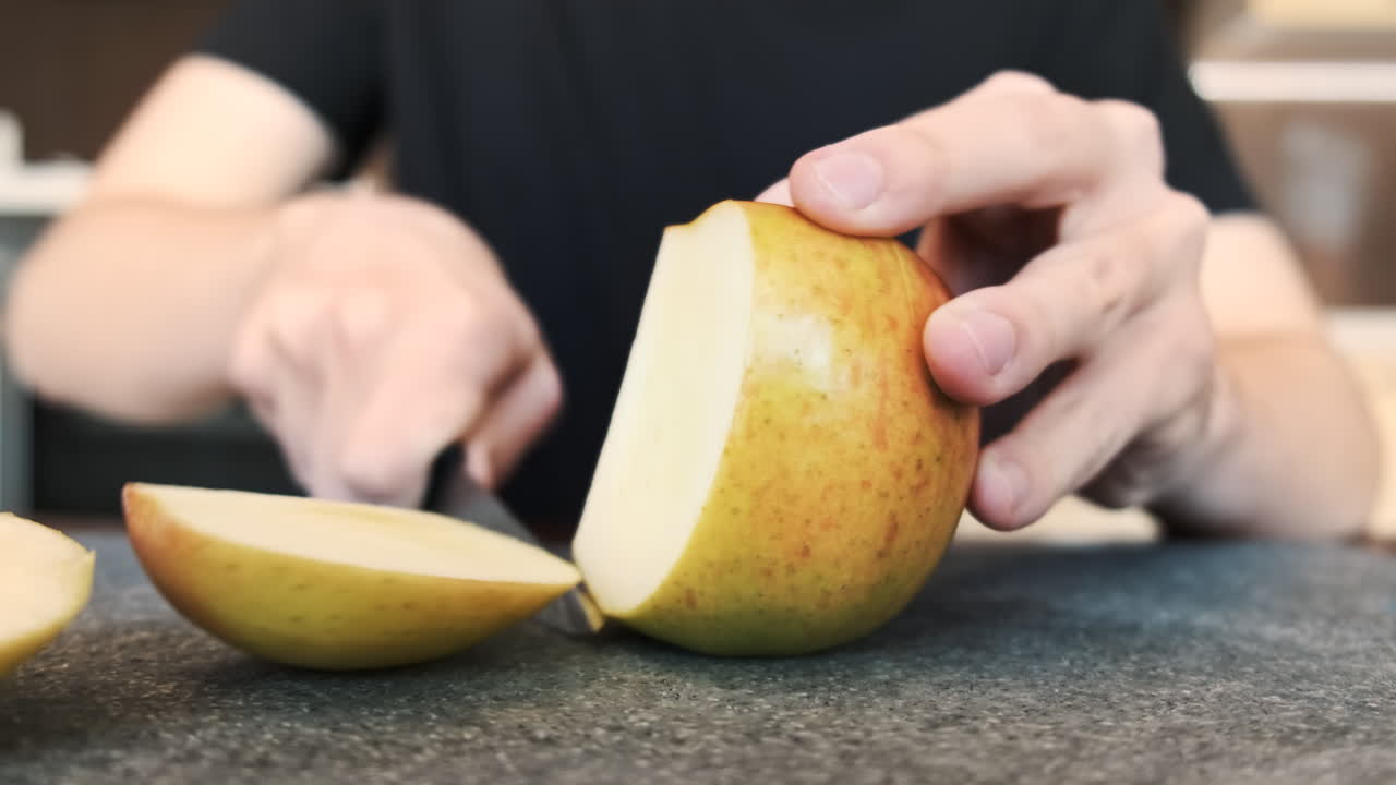 A man slicing an apple on a cooking board using a knife