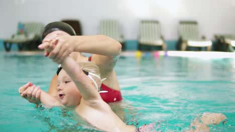 Zeitlupenaufnahme-Eines-Glücklich-Lächelnden-Kleinen-Kindes,-Das-Zusammen-Mit-Seiner-Mutter-Im-Schwimmbad-Schwimmt