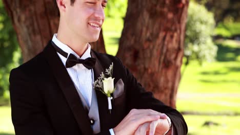 el novio feliz sonriendo a la cámara y mirando su reloj