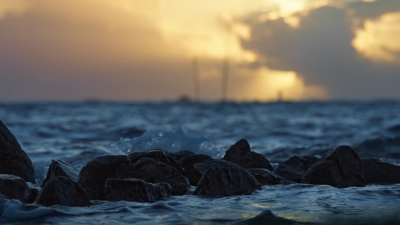 agua de mar en cámara lenta cinematográfica golpeando las rocas en la hermosa puesta de sol