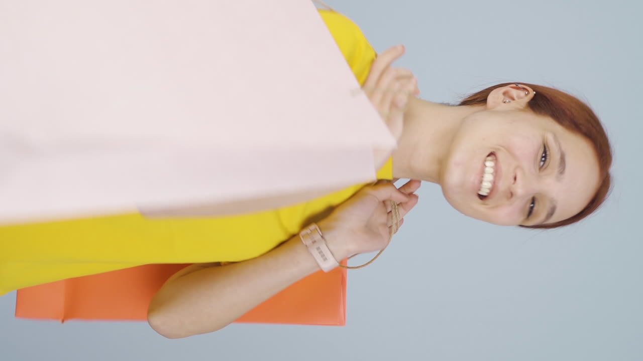 쇼핑 가방을 들고 춤추는 여성의 수직 비디오.