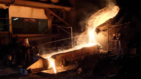 pouring liquid molten metal in a smelting furnace with a steel mill, heavy industry and metallurgic concept