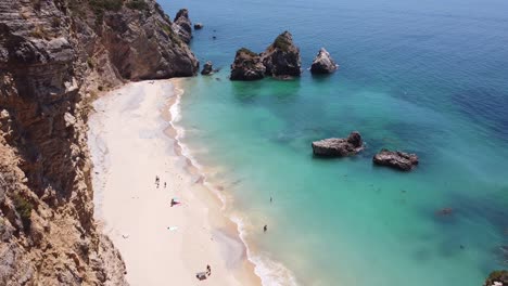 playa praia ribeira do cavalo cerca de sesimbra, alentejo, portugal - vista aérea de drones de la costa rocosa, playa de arena paradisíaca y mar turquesa