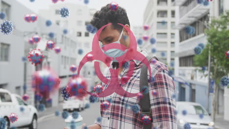 Animation of virus cells and biohazard sign over caucasian man wearing face mask