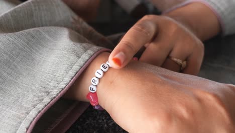 una mujer con una pulsera de amistad con la palabra "amigo" en ella.