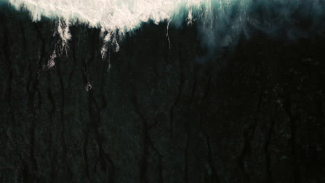 aerial birds eye view of dramatic dark moody ocean water with white foaming waves breaking