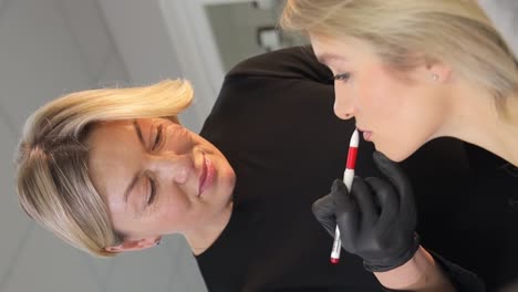 a beautician doing a permanent makeup procedure on the lips of a caucasian woman in a beauty salon a beautician doing a permanent makeup procedure on the lips of a caucasian woman in a beauty salon beauty concept permanent makeup for red lips of beautiful woman in beauty salon