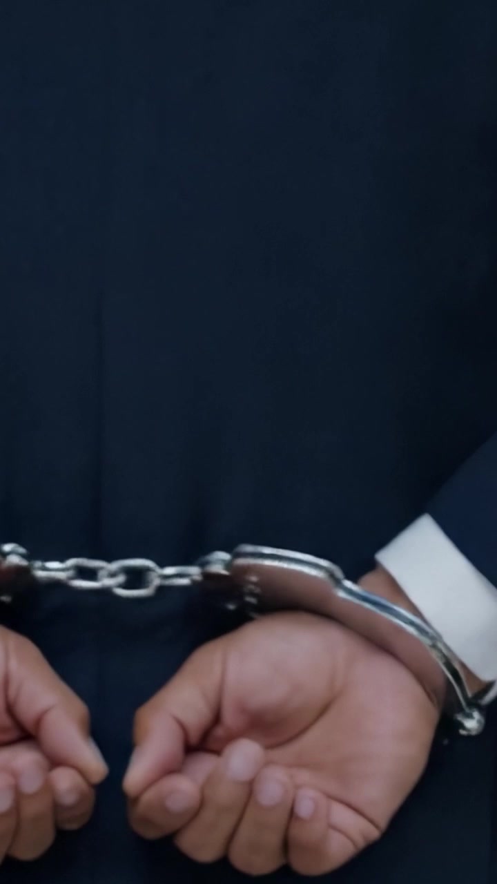 Questa rappresentazione mostra un paio di mani ammanettate, che simboleggiano la restrizione e l'autorità, trasmettendo temi di giustizia, applicazione della legge e la serietà del confinamento.
