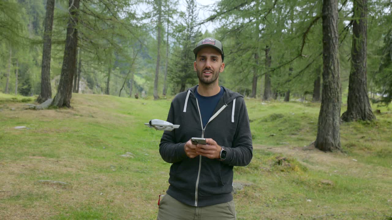Uomo con cappellino che testa il nuovo drone DJI Neo con una foresta sullo sfondo.