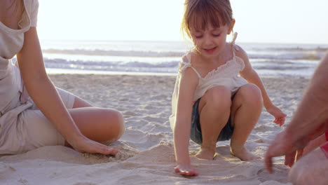 happy family playing on the beach drawing in the sand at sunset