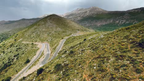 breathtaking aerial view of tiny curvy roads on majestic huge mountains, under the cloudy sky