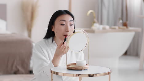 Woman Applying Lipstick in a Modern Bedroom