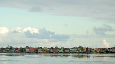 Bunte-Favela-Häuser-In-Der-Nähe-Eines-Sees-An-Einem-Sonnigen-Und-Bewölkten-Tag