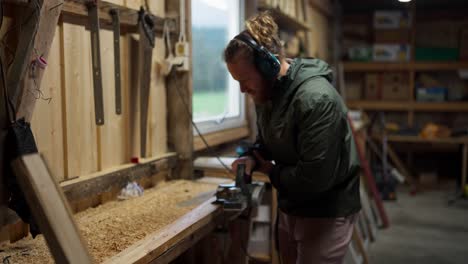 a man is employing an electric planer to achieve a smooth surface on the lumber for the construction of greenhouse - close up