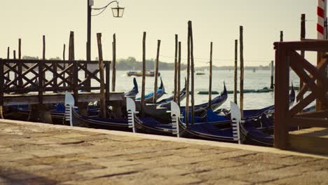 Gondolas,-typical-boats-from-Venice,-moving-on-the-water-in-the-lagoon-near-the-main-square