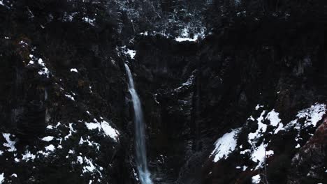 aerial shot of a waterfall surrounded by mountains and snow of a landscape in patagonia argentina