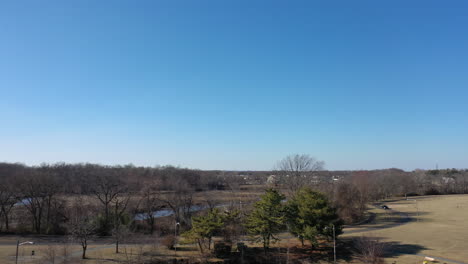 An-aerial-shot-over-an-open-field-with-a-pond-surrounded-by-dry-grass