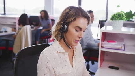 mujer de negocios profesional hablando por teléfono con auriculares en una oficina moderna en cámara lenta