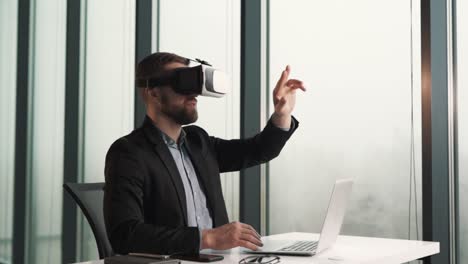 a man dressed in virtual reality glasses and business clothes sits at a table and flips through virtual pages