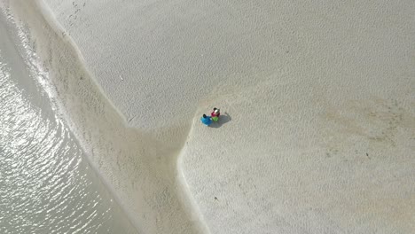 Vista-Aérea-De-Arriba-Hacia-Abajo-De-Una-Pareja-Romántica-Caminando-En-Una-Playa-En-Su-Cita,-Esposo-Y-Esposa-Caminando-Tomados-De-La-Mano