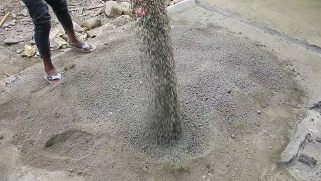 Indian mason worker pouring powder from a machine onto a cement surface at a construction site