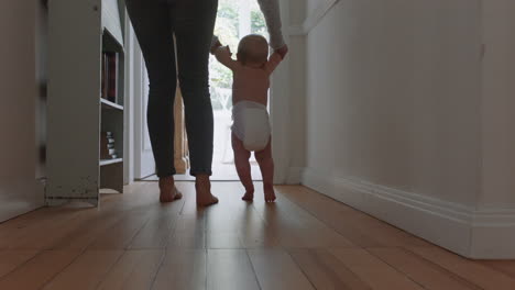 baby learning to walk toddler taking first steps with mother helping infant teaching child at home