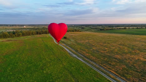 travel of romantic hot air balloon. red aerostat balloon flying over the fields under blue sky. beautiful aerostat in the form of a heart.aerial view.