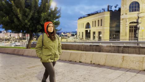 young woman walking and observing in urban environment at dusk