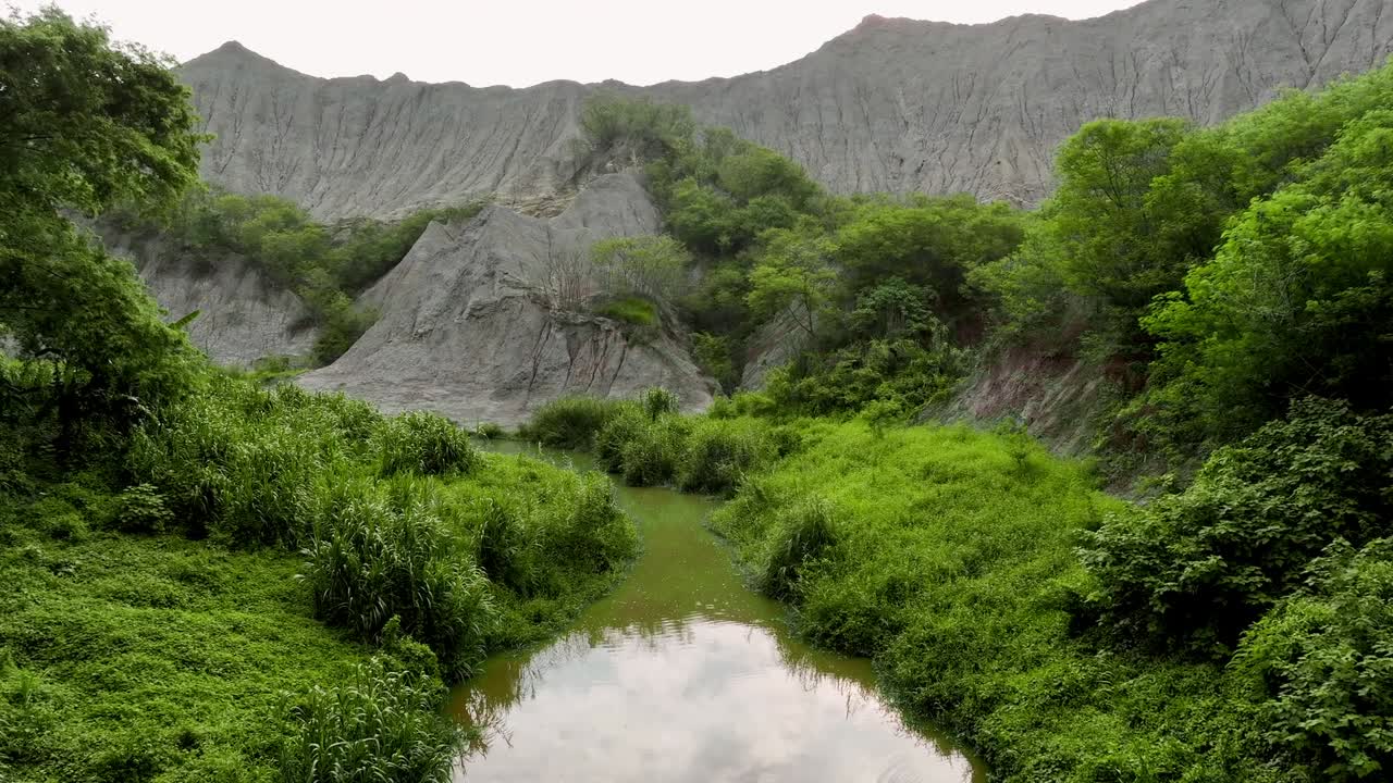 Aerial flyover curvy natural river in moon world badlands of Taiwan, Asia at daytime